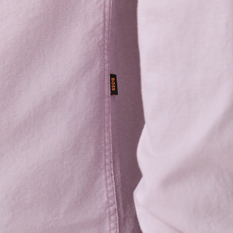 Close-up of a light pink shirt with a brand logo on the collar.